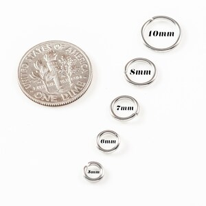 May include: Five silver jump rings in different sizes, ranging from 5mm to 10mm. The rings are arranged in a row from smallest to largest, with a US dime coin for scale.