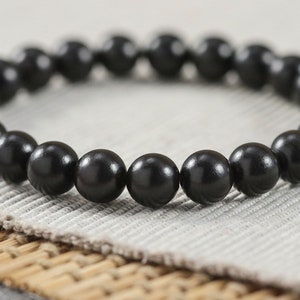 Puede incluir: Un brazalete negro con cuentas redondas.