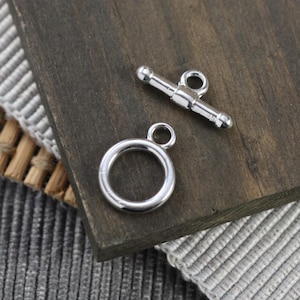 May include: Silver toggle clasp with a round ring. The clasp is made of metal and has a polished finish.