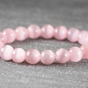 May include: A pink gemstone bracelet with round beads. The bracelet is made of natural stones and has a smooth, polished finish.
