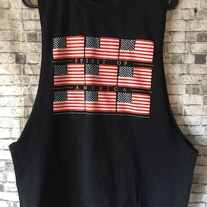 May include: Black sleeveless shirt with a graphic of multiple American flags and the text "Spirit of America".