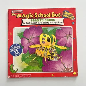 Può includere: Un libro per bambini intitolato "The Magic School Bus Plants Seeds" con una copertina rossa. La copertina presenta un autobus scolastico giallo trasformato in un'ape, circondato da fiori viola. Il libro è di Scholastic.
