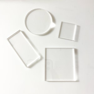 May include: Four clear acrylic shapes: a circle, a square, and two rectangles. The shapes are arranged on a white surface.