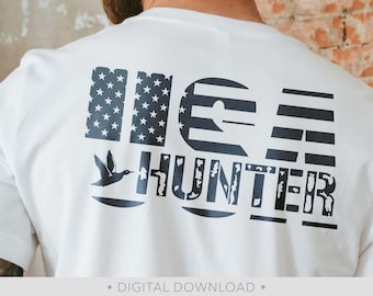 May include: A white t-shirt with a blue and white design that says "USA HUNTER" with a stylised image of a duck flying.