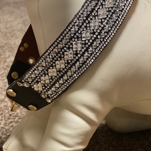 May include: A brown leather dog collar with a diamond-shaped pattern of clear rhinestones.