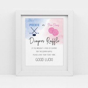 May include: A white framed sign with a blue and pink watercolor background. The sign says "PUCKS or Pom Poms Diaper Raffle" and includes instructions for guests to leave their raffle ticket if they brought diapers.
