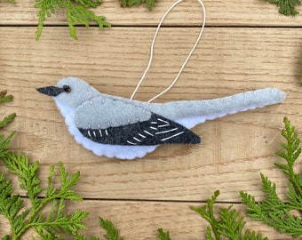 May include: A felt ornament of a gray and black bird with a white string loop for hanging.