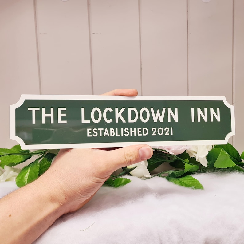 May include: A green and white sign that reads "The Lockdown Inn Established 2021".