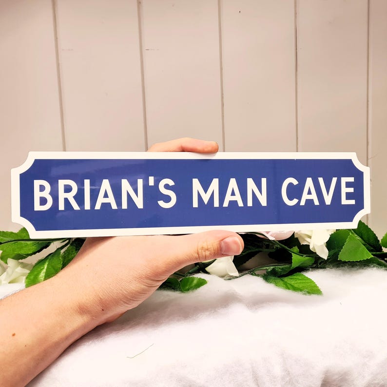May include: A blue and white sign with the text "BRIAN'S MAN CAVE" in white letters.