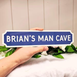 May include: A blue and white sign with the text "BRIAN'S MAN CAVE" in white letters.
