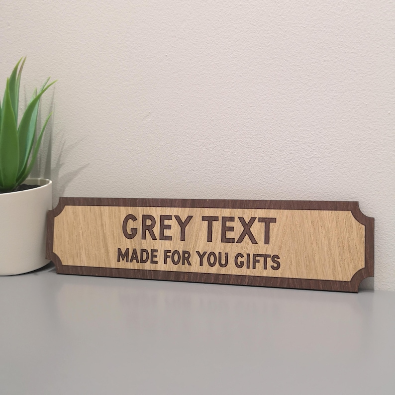 May include: A wooden sign with a brown border and a light wood center. The sign has the text "GREY TEXT MADE FOR YOU GIFTS" engraved on it.