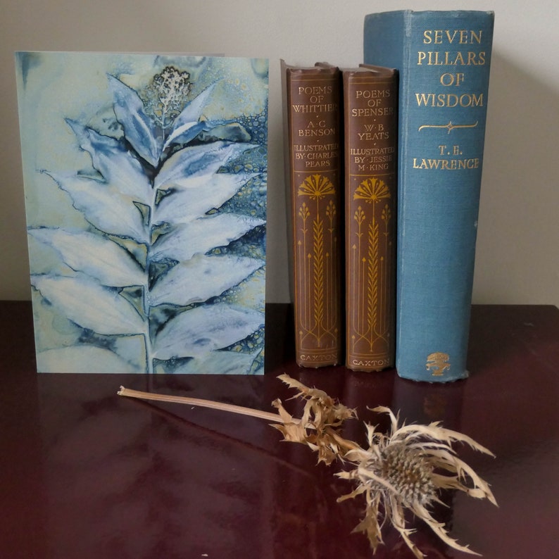 May include: A blue and white watercolor painting of a plant with leaves. Three books are on a shelf behind the painting. The books are titled "Poems of Whittie", "Poems of Spenser", and "Seven Pillars of Wisdom".