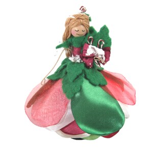 May include: A handmade felt and fabric doll wearing a green dress, red and white ribbon, and holding a candy cane.