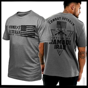 Puede incluir: Camiseta gris con una bandera estadounidense desgastada y el texto "Combat Veteran American Patriot" en la parte delantera. La parte posterior de la camiseta tiene el texto "Combat Veteran" en un triángulo con el texto "Battle of Ramadi Iraq" debajo.