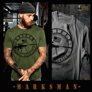 May include: Green and gray t-shirts with a black and white graphic print of a sniper rifle and the text "Sniper from a place you will not see comes a sound you will not hear deadly accuracy".