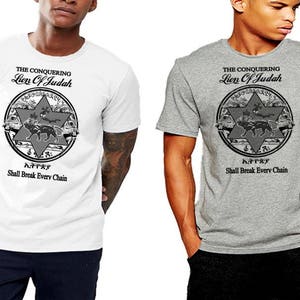 Puede incluir: Dos camisetas con un diseño gráfico de un león en un círculo con el texto "The Conquering Lion of Judah" y "Shall Break Every Chain" en negro. La camiseta de la izquierda es blanca y la camiseta de la derecha es gris.