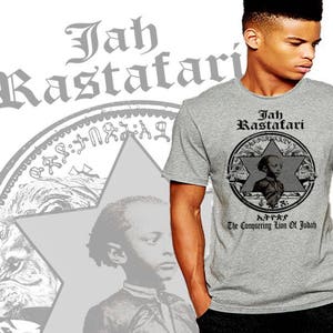 Puede incluir: Una camiseta gris con una impresión negra de una estrella con un león dentro. El texto "Jah Rastafari" está por encima de la estrella y "The Conquering Lion of Judah" está por debajo de la estrella. El texto está en una fuente negra.