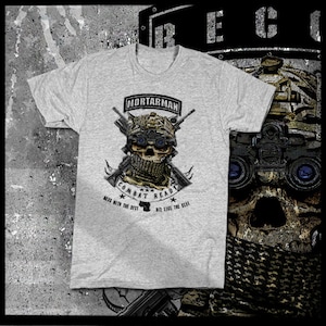 Könnte beinhalten: Graues T-Shirt mit einem Schädel, der einen Militärhelm und eine Schutzbrille trägt. Der Schädel hält zwei Gewehre und hat ein Bandana um den Hals. Der Text "Mortarman Combat Ready" befindet sich über dem Schädel. Der Text "Mess with the best, die like the rest" befindet sich unter dem Schädel.