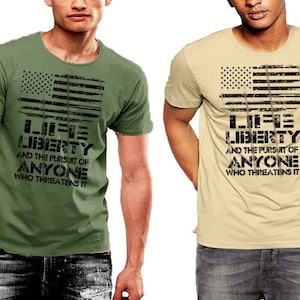 May include: Two men's t-shirts with a distressed American flag design and the text "Life Liberty and the pursuit of anyone who threatens it". The shirts are in green and beige.