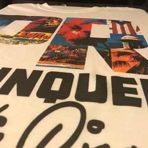 May include: White t-shirt with a graphic design of the letters "DR" made up of images of tropical scenes, palm trees, and the Puerto Rican flag. The text "RINQUEN" is printed in black below the letters.