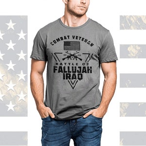 May include: A gray t-shirt with a black graphic design. The graphic features a triangle with the words "Combat Veteran" at the top, an American flag in the center, and the words "Battle of Fallujah Iraq" at the bottom.