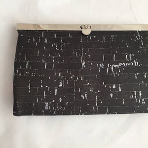 May include: A black and white cork clutch with a silver clasp.
