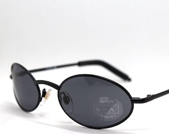 May include: Black oval sunglasses with a thin metal frame and dark gray lenses. The lenses have a UV 100% and Category 3 label.