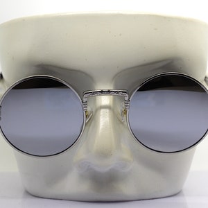 K&ouml;nnte beinhalten: Silberne runde Sonnenbrille mit verspiegelten Gl&auml;sern und filigranen Details an den B&uuml;geln.