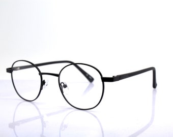 May include: Black metal round frame spectacles with clear lenses.