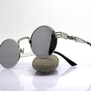 K&ouml;nnte beinhalten: Silberne runde Sonnenbrille mit einem einzigartigen, filigranen und detaillierten Metallrahmen. Die Sonnenbrille hat dunkelgraue Gl&auml;ser.
