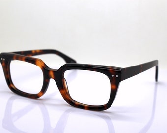 Puede incluir: Gafas de pasta de carey con montura cuadrada y lentes transparentes.