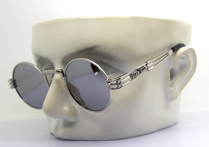K&ouml;nnte beinhalten: Silberne runde Sonnenbrille mit einem einzigartigen, filigranen und detaillierten Metallrahmen. Die Sonnenbrille hat verspiegelte Gl&auml;ser.