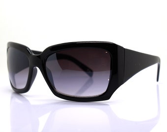Puede incluir: Gafas de sol rectangulares negras con lentes de degradado gris oscuro.