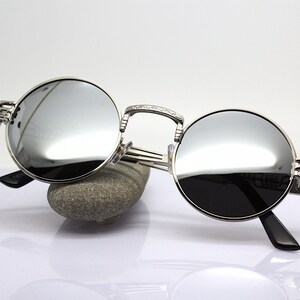 K&ouml;nnte beinhalten: Silberne runde Sonnenbrille mit verspiegelten Gl&auml;sern und aufwendigen Metalldetails an den B&uuml;geln.