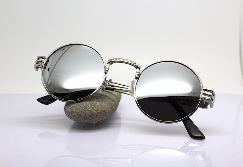K&ouml;nnte beinhalten: Silberne runde Sonnenbrille mit verspiegelten Gl&auml;sern und aufwendigen Metalldetails an den B&uuml;geln.