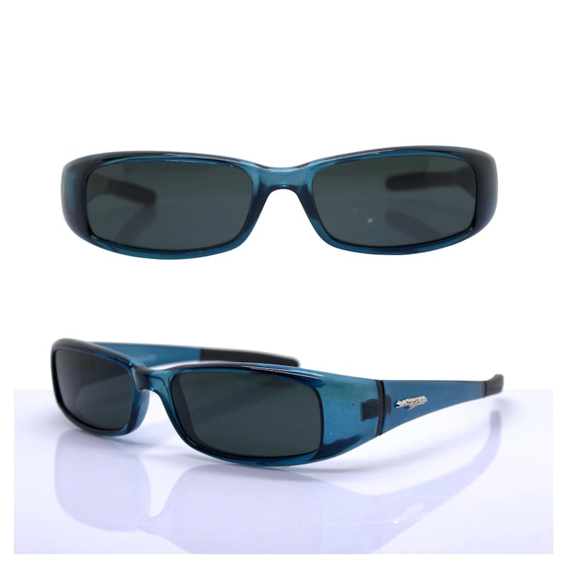 May include: Blue sunglasses with dark lenses. The frames are a translucent blue, and the lenses are a dark gray. The sunglasses have a rectangular shape and a curved design. The image shows the sunglasses from two different angles.