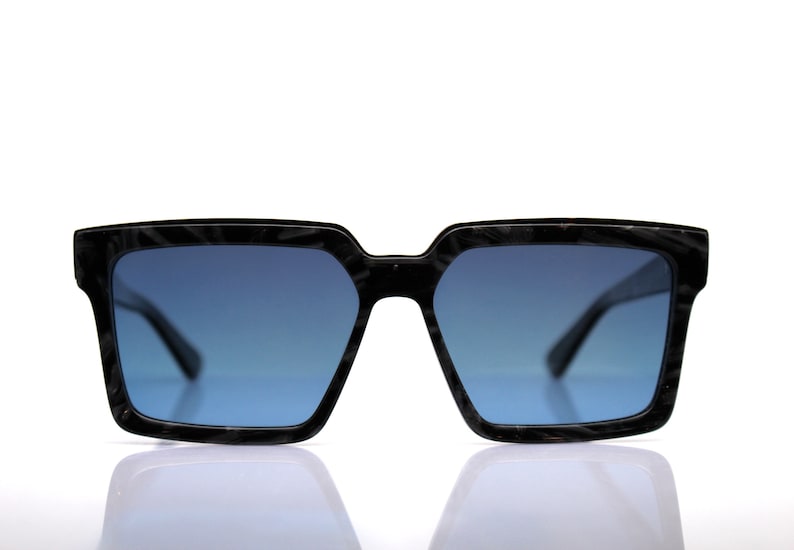 May include: Black sunglasses with a dark blue lens and a textured frame.