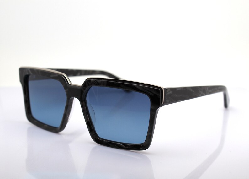 May include: Black square-shaped sunglasses with blue lenses and a black and silver frame.