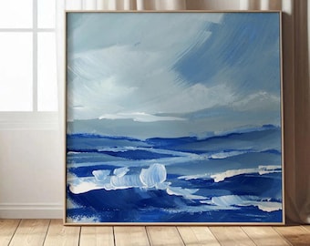 May include: Abstract landscape painting in shades of blue and white. The artwork features broad brushstrokes depicting a cloudy sky and rolling hills. The painting is framed in a light wood frame and displayed on a wooden floor.