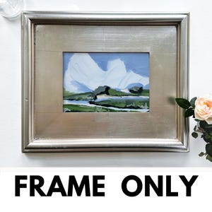 May include: Silver-toned rectangular picture frame with a landscape painting inside. The painting features a mountain scene with blue, white, and green brushstrokes. The text "FRAME ONLY" is at the bottom of the image.