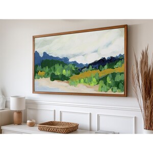 May include: A framed abstract landscape painting with a light blue, green, and yellow color scheme. The painting depicts a mountain range with a cloudy sky.