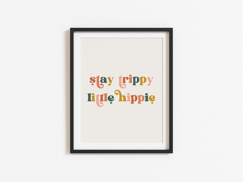 Pode incluir: Uma impress&atilde;o emoldurada com o texto "stay trippy little hippie" em uma fonte retr&ocirc;. O texto est&aacute; em tons de rosa, laranja, verde e marrom.