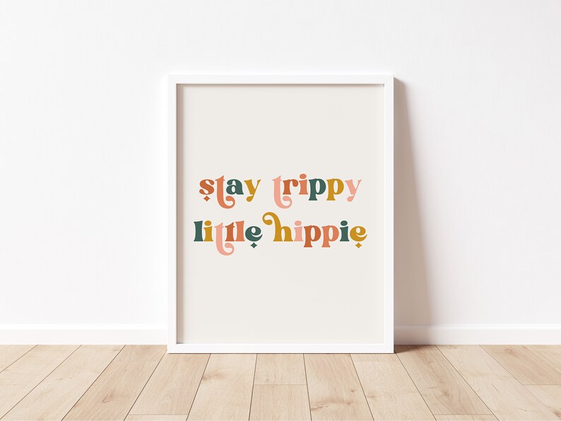Pode incluir: Uma impress&atilde;o emoldurada branca com o texto "stay trippy little hippie" em letras estilizadas coloridas.