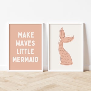 May include: Two framed prints with a peach background. The left print has the text "Make Waves Little Mermaid" in white. The right print has a pink mermaid tail.