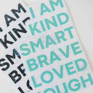 May include: A sheet of white vinyl with turquoise lettering that reads "I am kind smart brave loved enough".