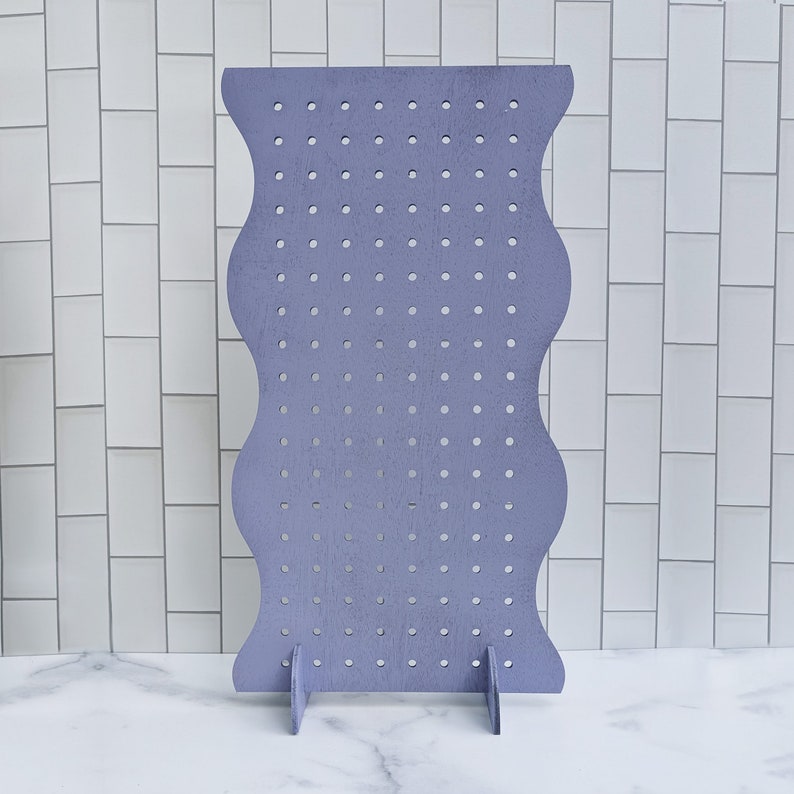 May include: A purple earring display stand with a wavy design and multiple holes for hanging earrings.