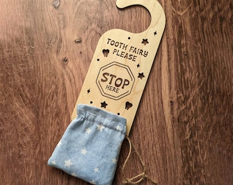 May include: Wooden tooth fairy door hanger with a blue and white star patterned pouch attached. The door hanger has the text "Tooth Fairy Please" and a stop sign with the text "Stop Here".