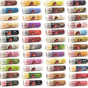 Könnte beinhalten: Eine Sammlung von Lippenbalsam in transparenten Tuben, jede mit einem einzigartigen Geschmacksnamen wie "Apple Cider" und "Raspberry". Die Lippenbalsame haben farbenfrohe Etiketten und sind in einem Raster angeordnet.