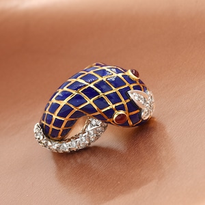 May include: A gold ring with a blue enamel snake design. The snake is decorated with a diamond and ruby accents.