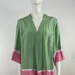 Op de afbeelding: Een groene en roze kimono-achtige robe met een V-hals en korte mouwen. De mouwen hebben een geometrisch patroon in blauw, roze en wit.